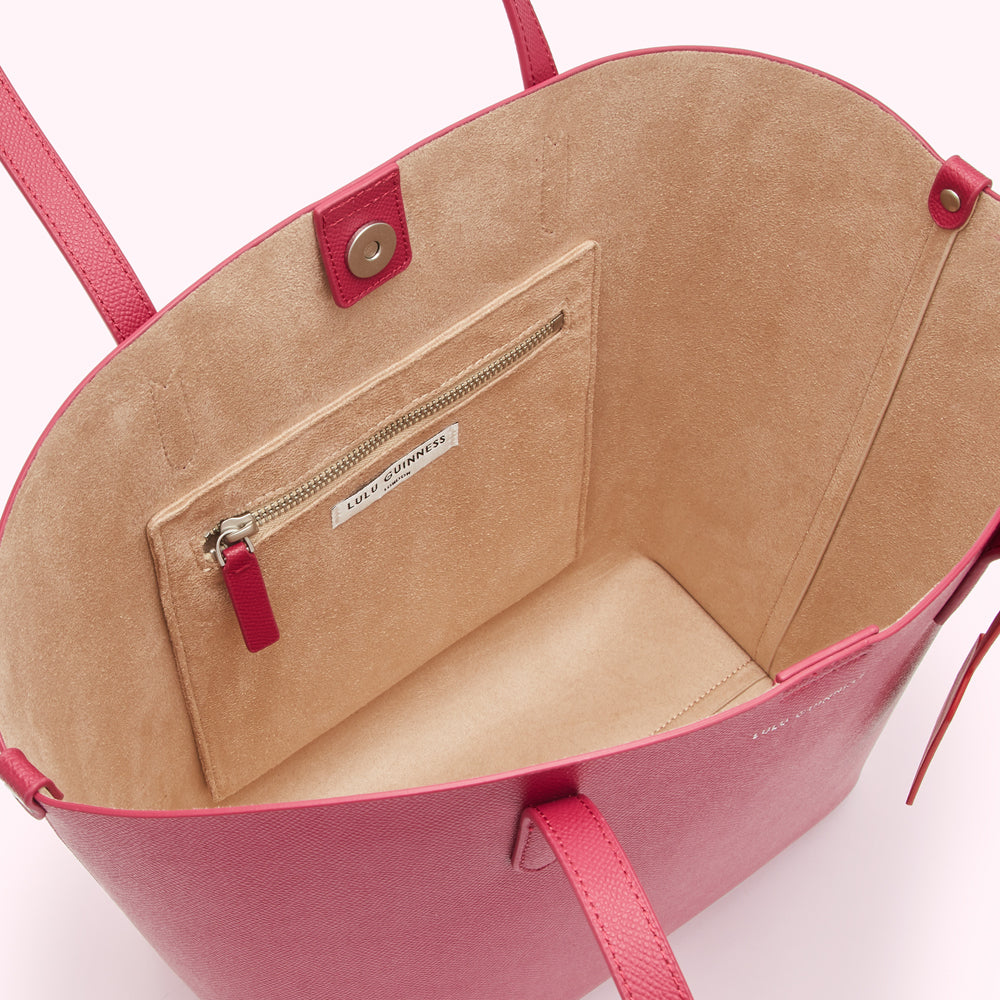 Inside of a pink Lulu Guinness tote bag showing a beige interior and a zippered pocket.
