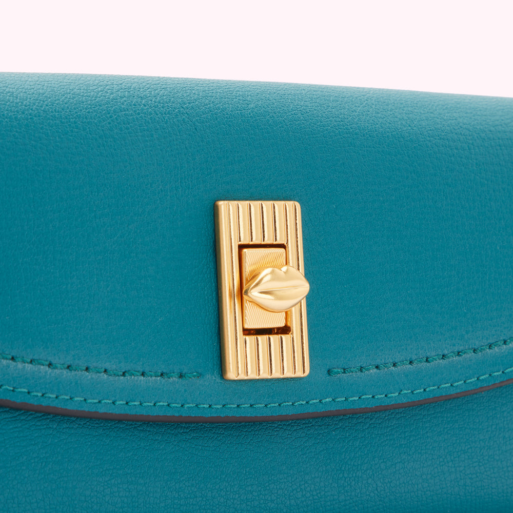Close-up of teal leather purse with gold lip-shaped clasp.
