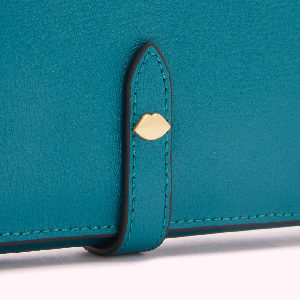 Close-up of a teal leather wallet with a gold lip-shaped clasp.
