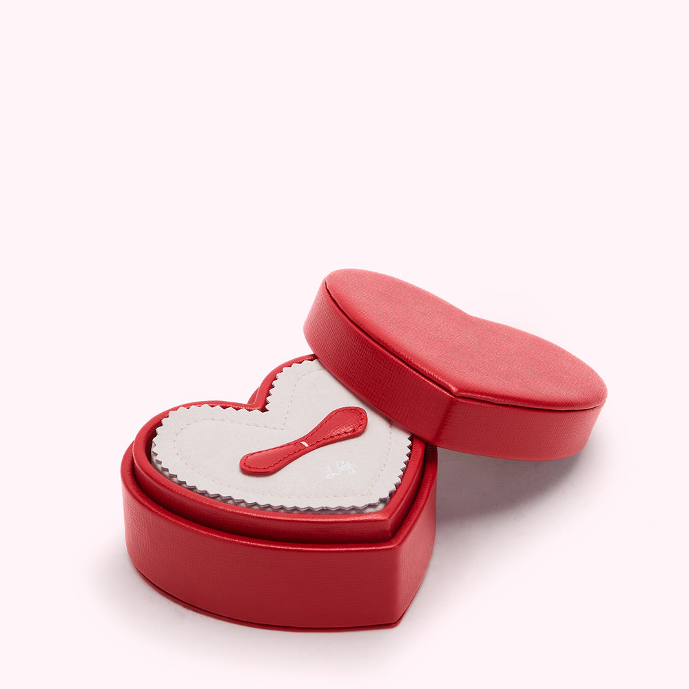 Red heart-shaped jewellery box with a pink heart-shaped insert and a small red polishing cloth.
