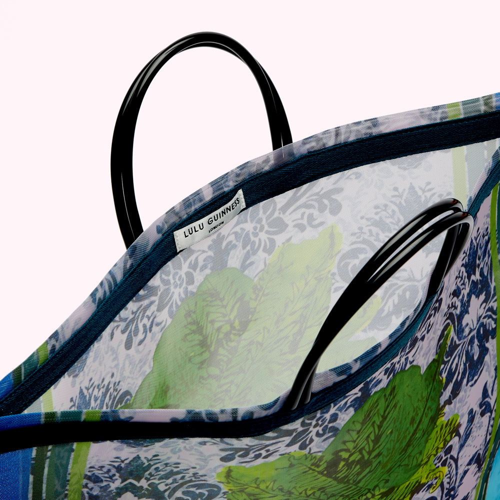 Close-up view of the inside of a Lulu Guinness tote bag. The bag is made of a sheer fabric with a floral print and features black handles. The Lulu Guinness London label is visible.
