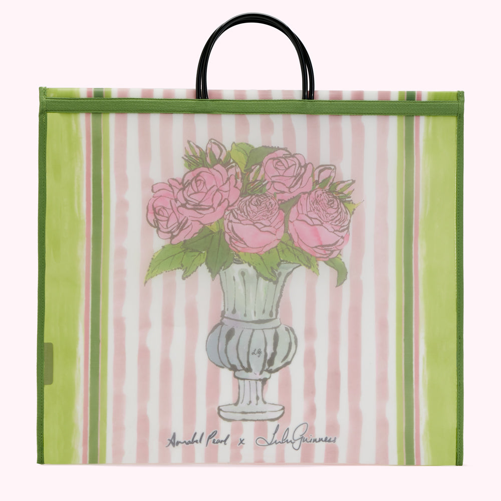 Large green and pink striped tote bag with a drawing of pink roses in a vase. The bag has black handles and the text "Annabel Pearl x Lulu Guinness" is printed on the bottom.
