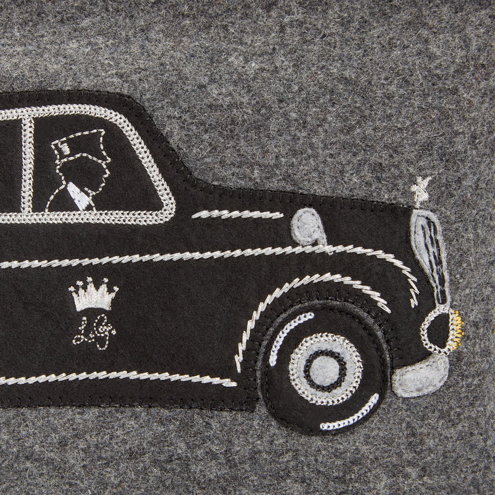 Close-up of embroidered black London taxi cab appliqué© on grey felt.