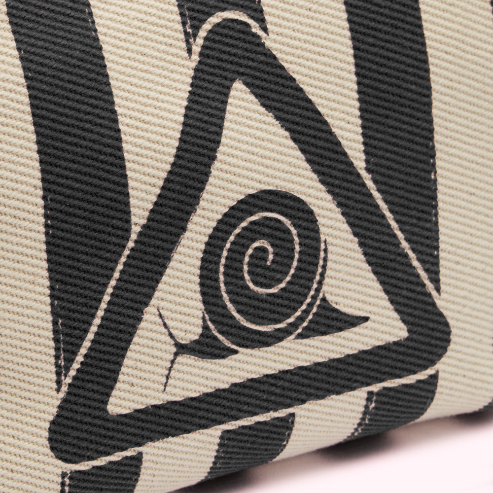 Close-up of a beige textile with a black triangle and spiral design.