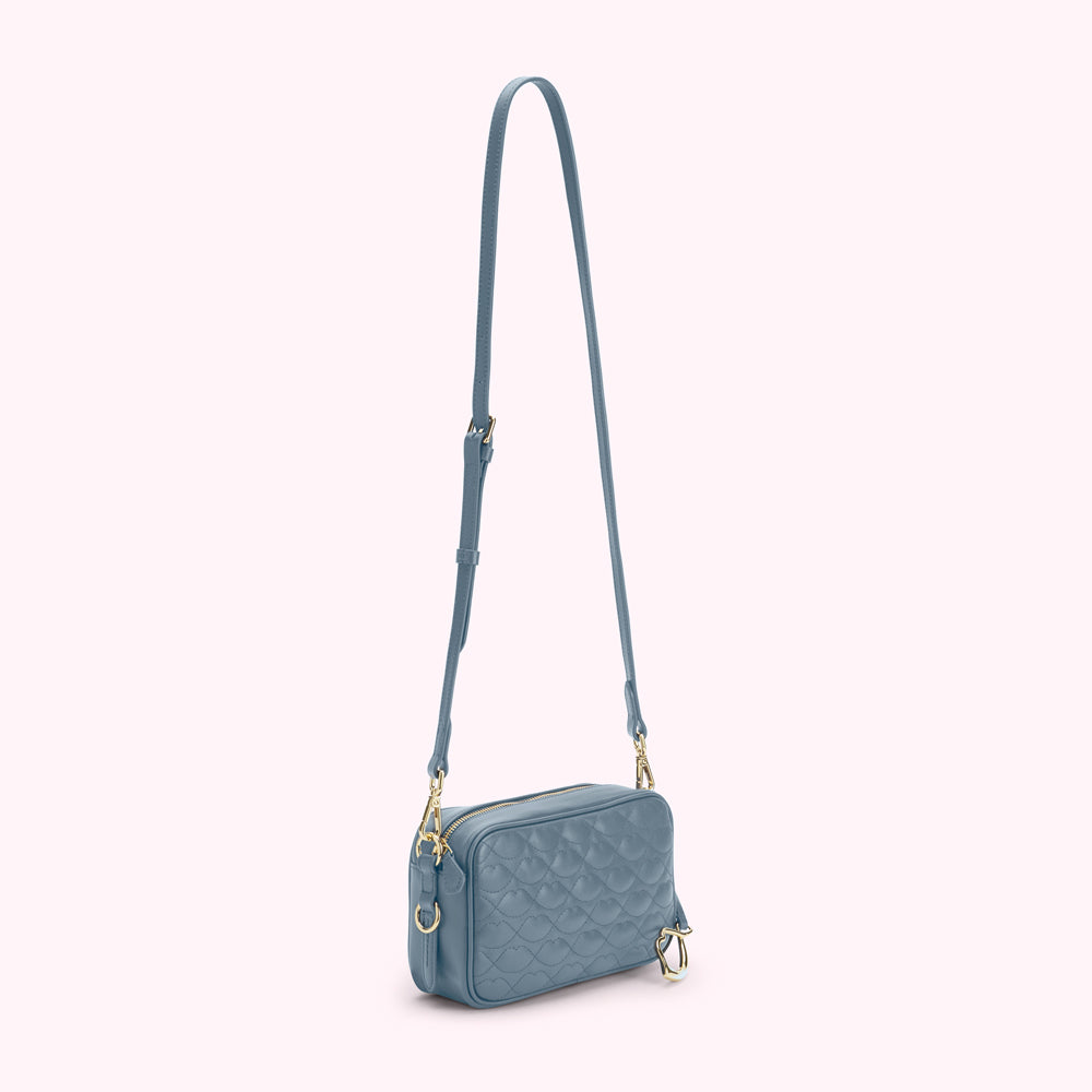 A dusty blue quilted crossbody bag with gold hardware.