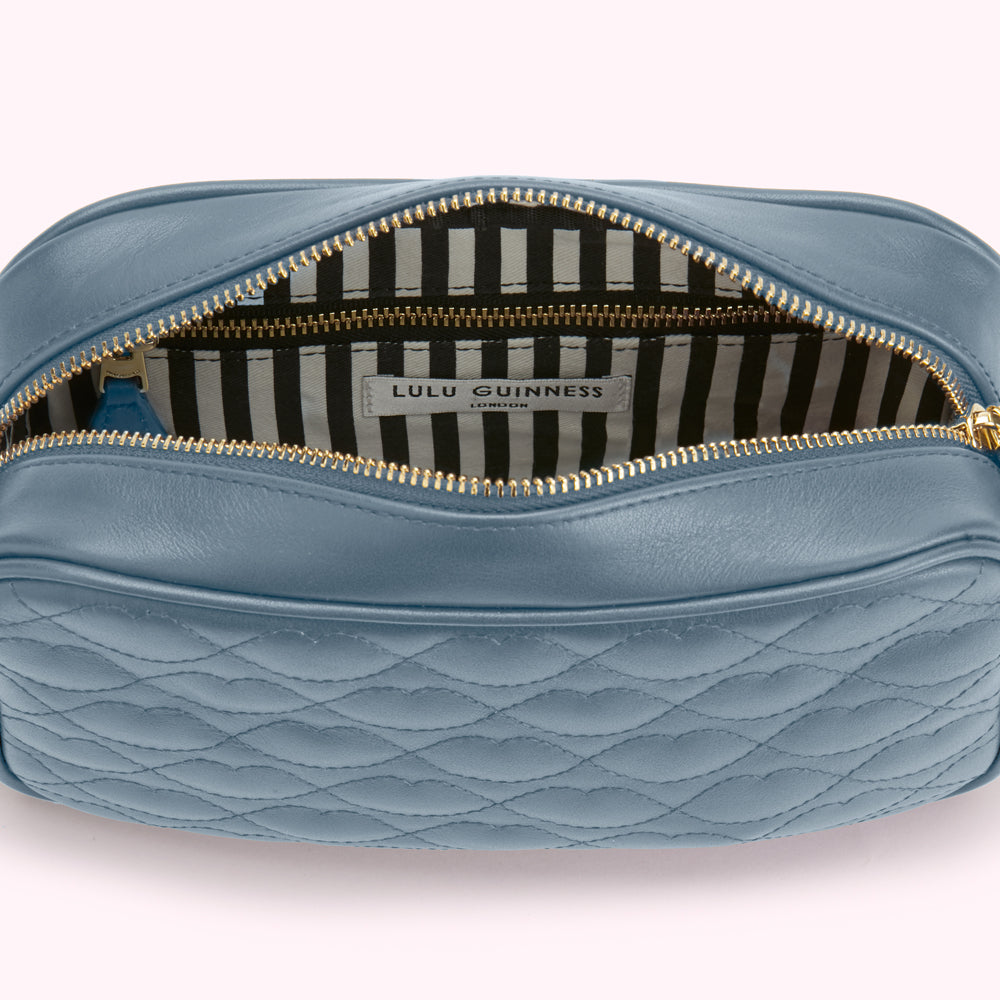 Open blue quilted Lulu Guinness crossbody bag with black and white striped interior.