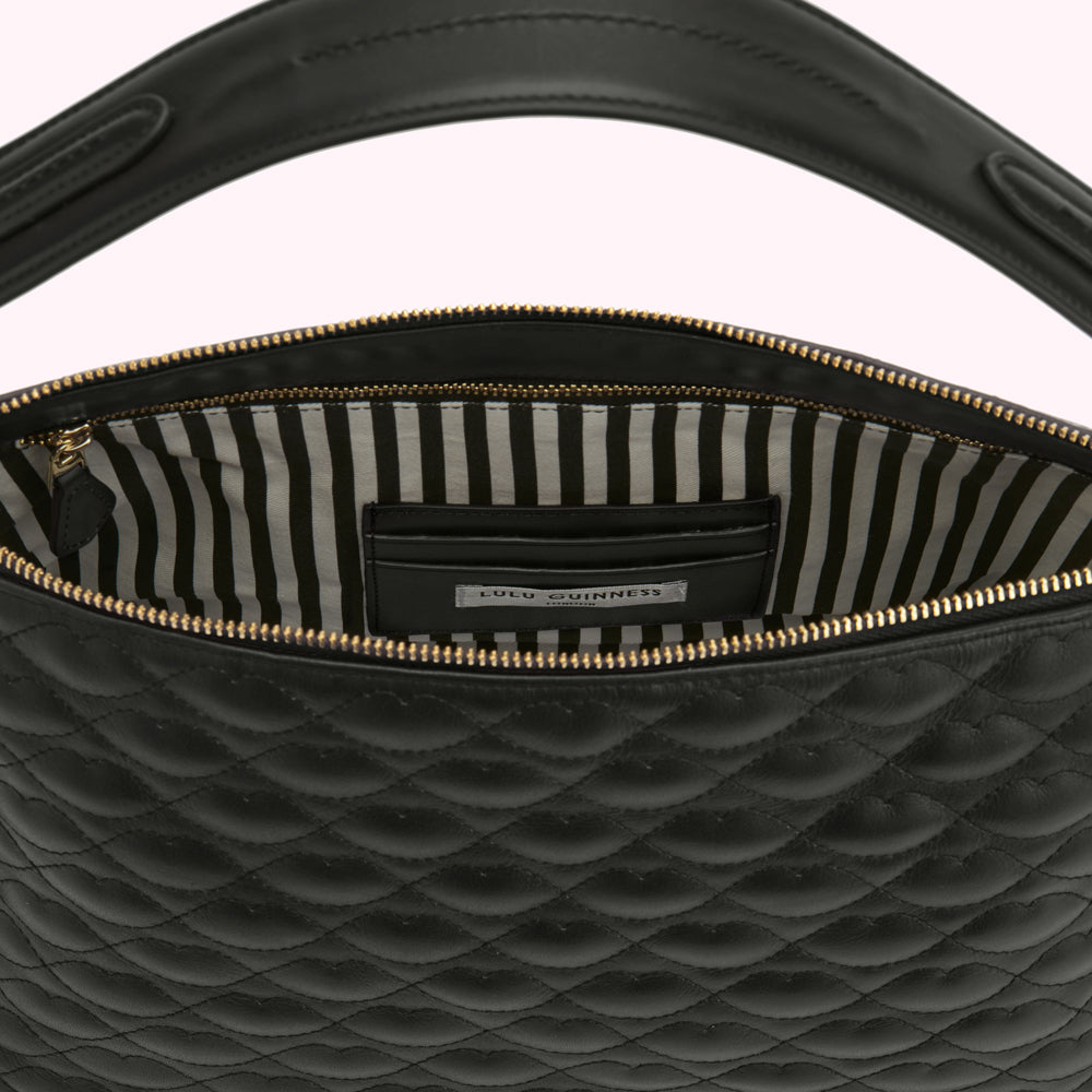 Black quilted leather Lulu Guinness handbag open to show black and white striped interior and brand label.
