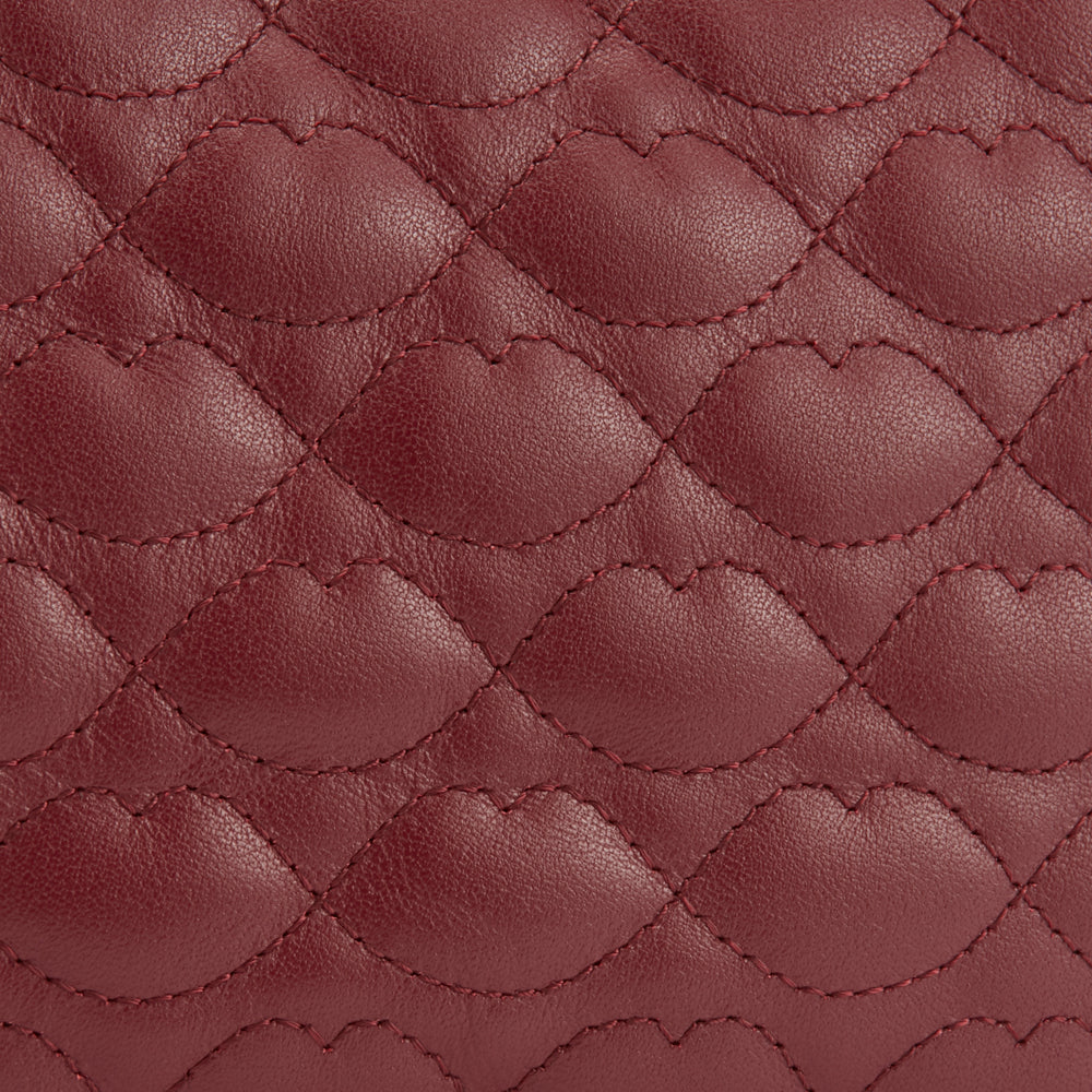 Close-up of quilted burgundy leather with a lip-shaped pattern.
