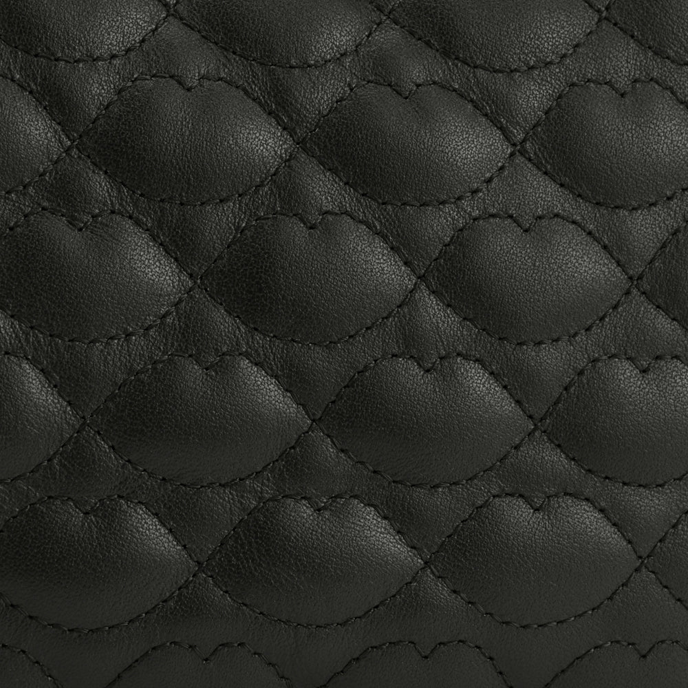 Close-up of black quilted leather with a repeating lip-shaped pattern.
