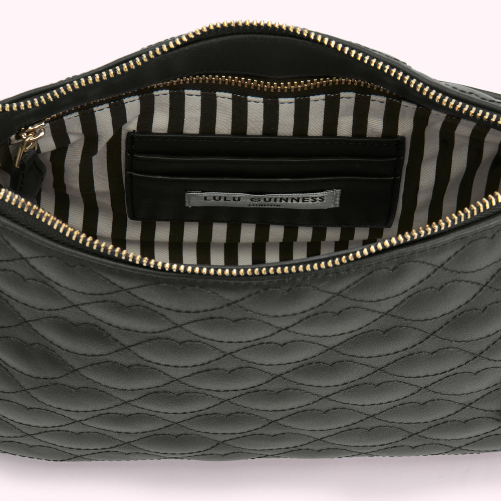 Black quilted Lulu Guinness pouch open to reveal a black and white striped interior with a brand label.
