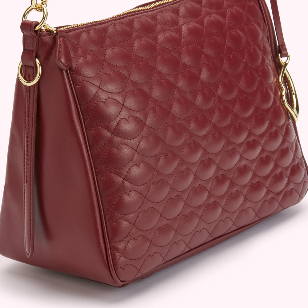Close-up of a dark red quilted leather handbag with gold-toned hardware.
