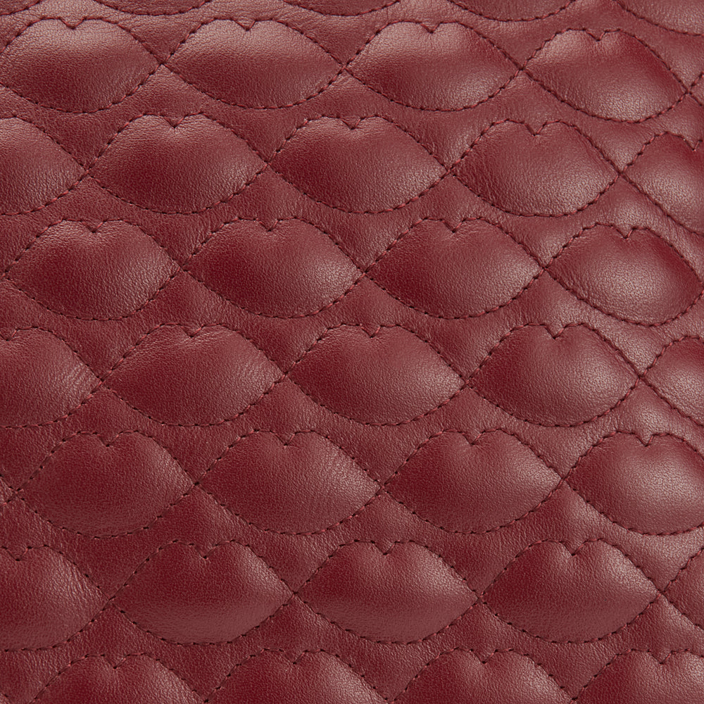 Close-up of quilted burgundy leather with a lip-shaped pattern.
