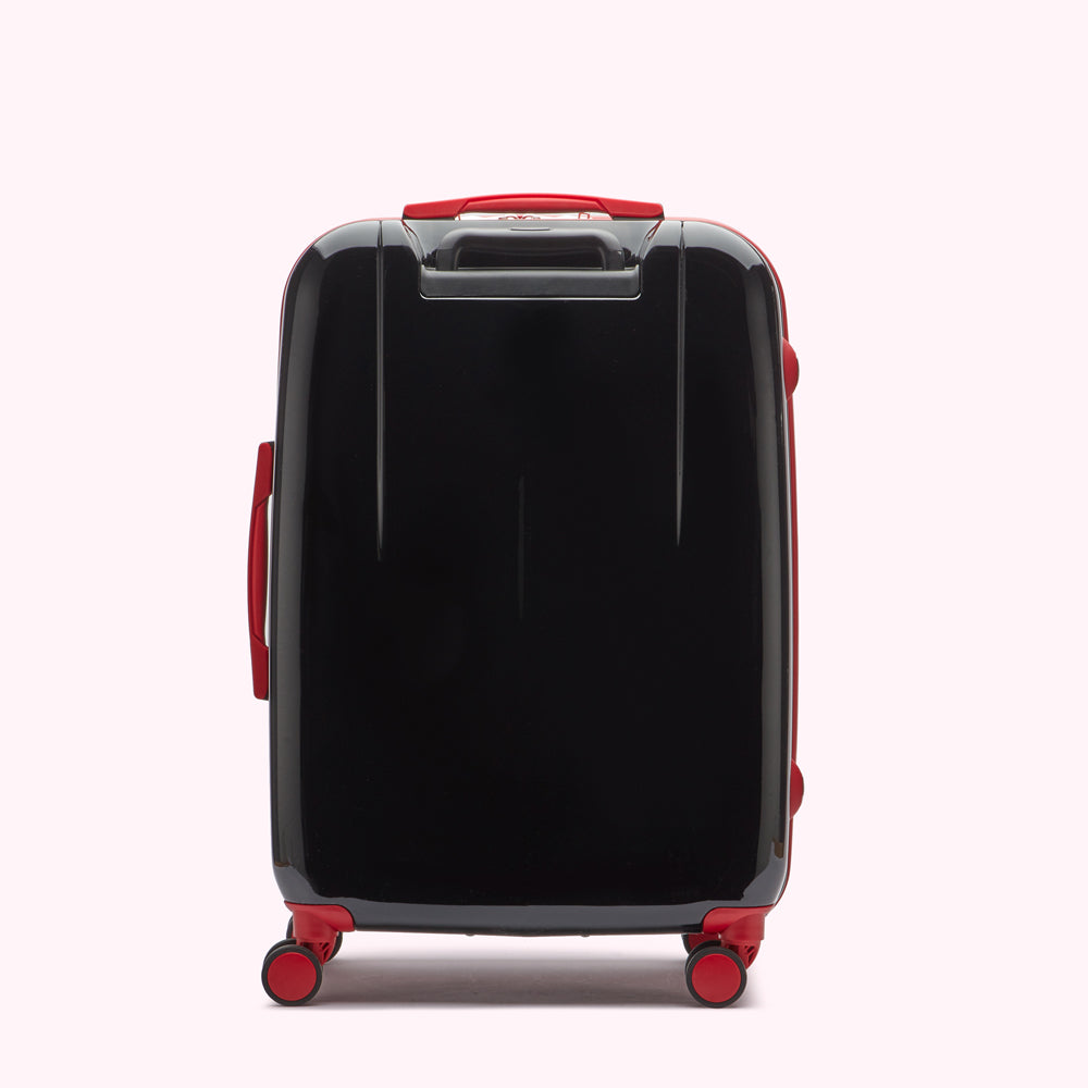 Rear view of a black suitcase with red accents against a white background.
