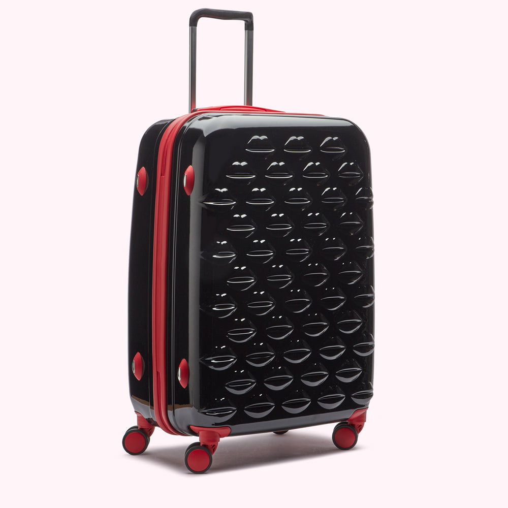 Black suitcase with red accents and a lip print design.
