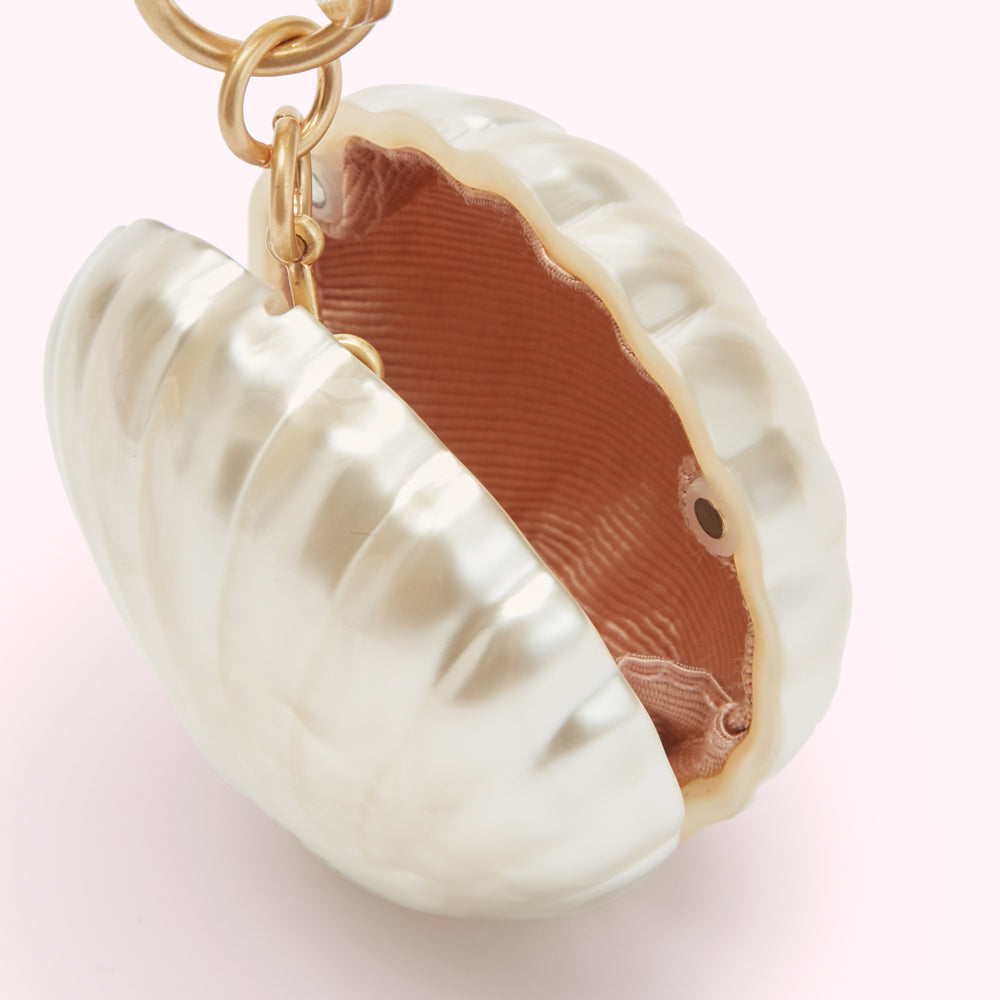 Close-up of a pearl-like clam shell-shaped bag with a gold clasp.
