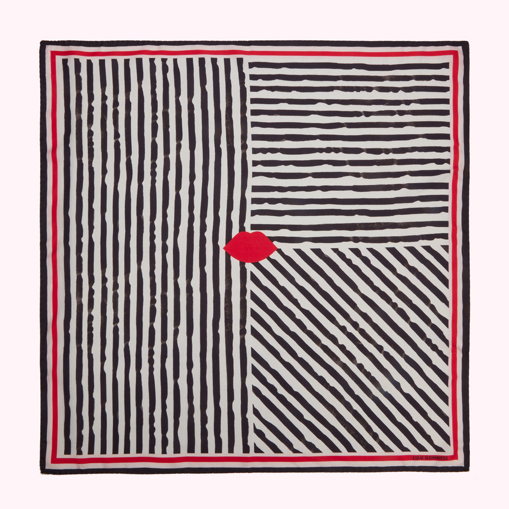 A cream-colored square scarf with a black and white striped pattern, featuring a single red lip in the centre. The scarf has a red border.