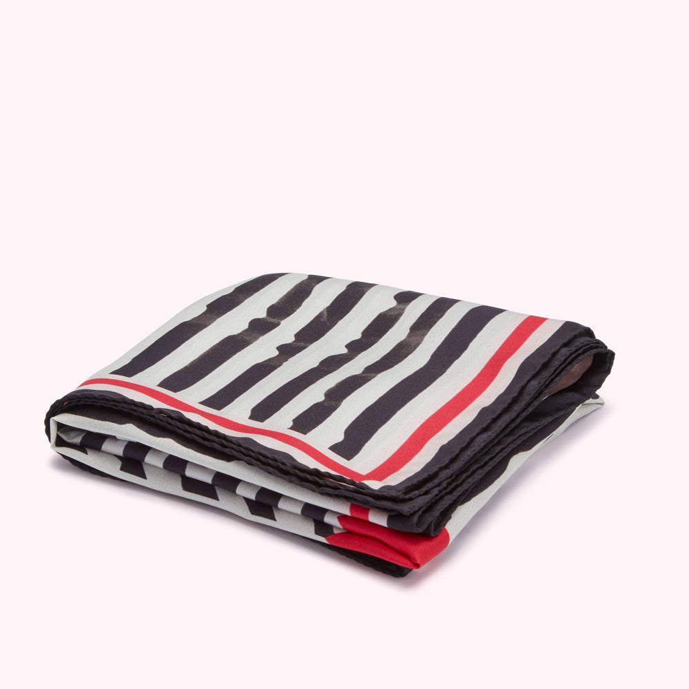 Folded scarf with black and white stripes and red trim.
