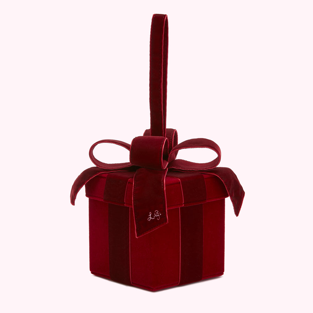 A dark red velvet gift box-shaped handbag with a matching bow and handle.
