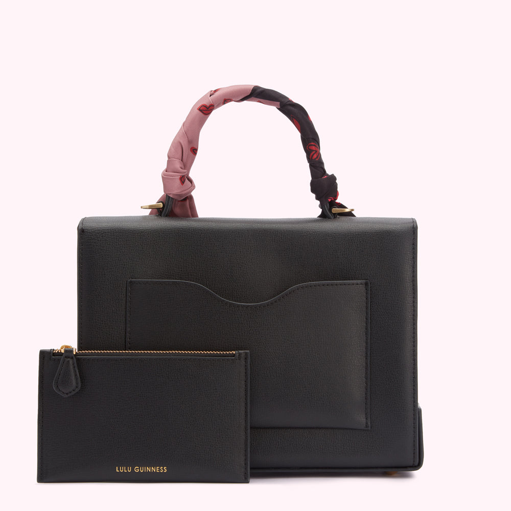 Black Lulu Guinness handbag with a pink and red patterned scarf handle and a matching zip-around pouch.
