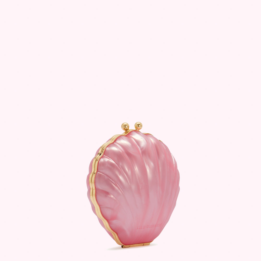 Pink seashell-shaped clutch with gold clasp on white background.
