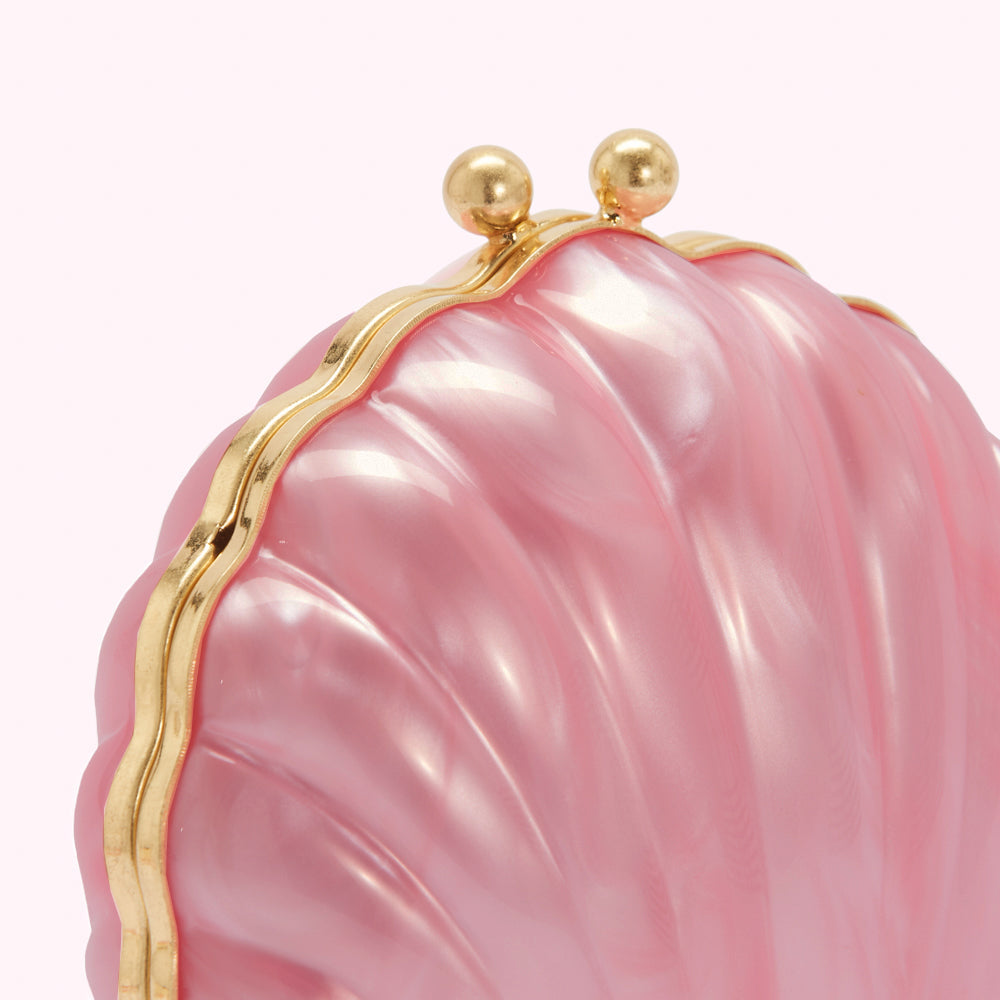 Close-up of a pink shell-shaped clutch with a gold clasp.
