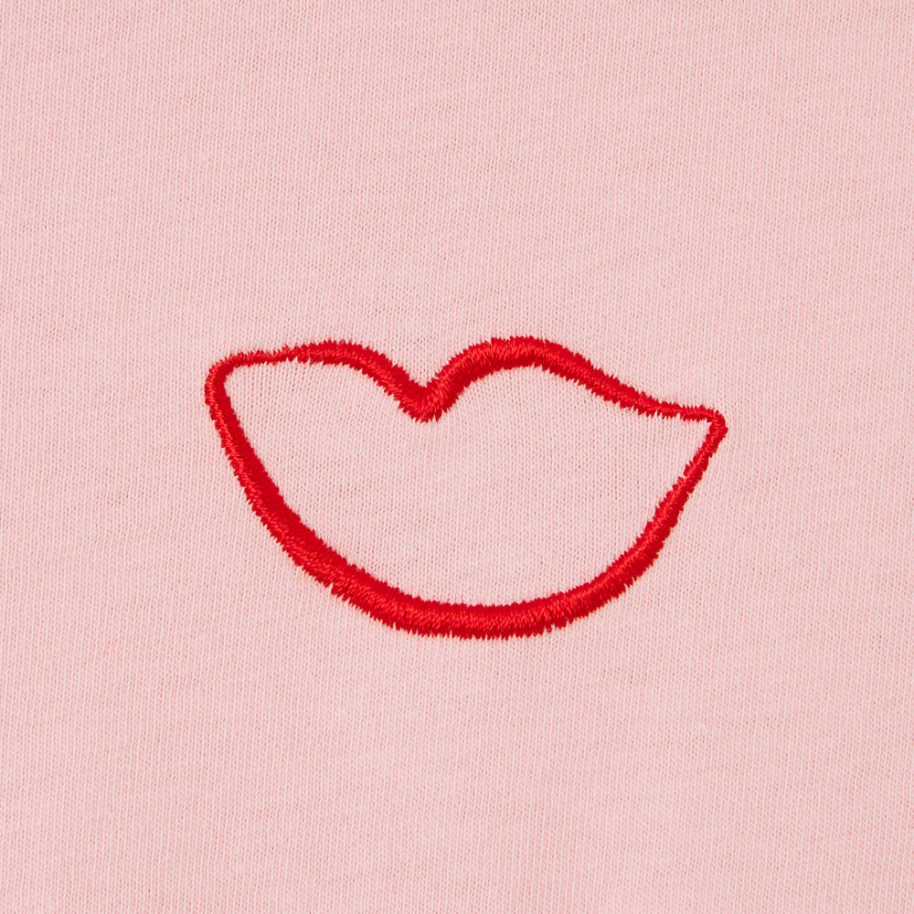 Red lips embroidered on a pink fabric background.
