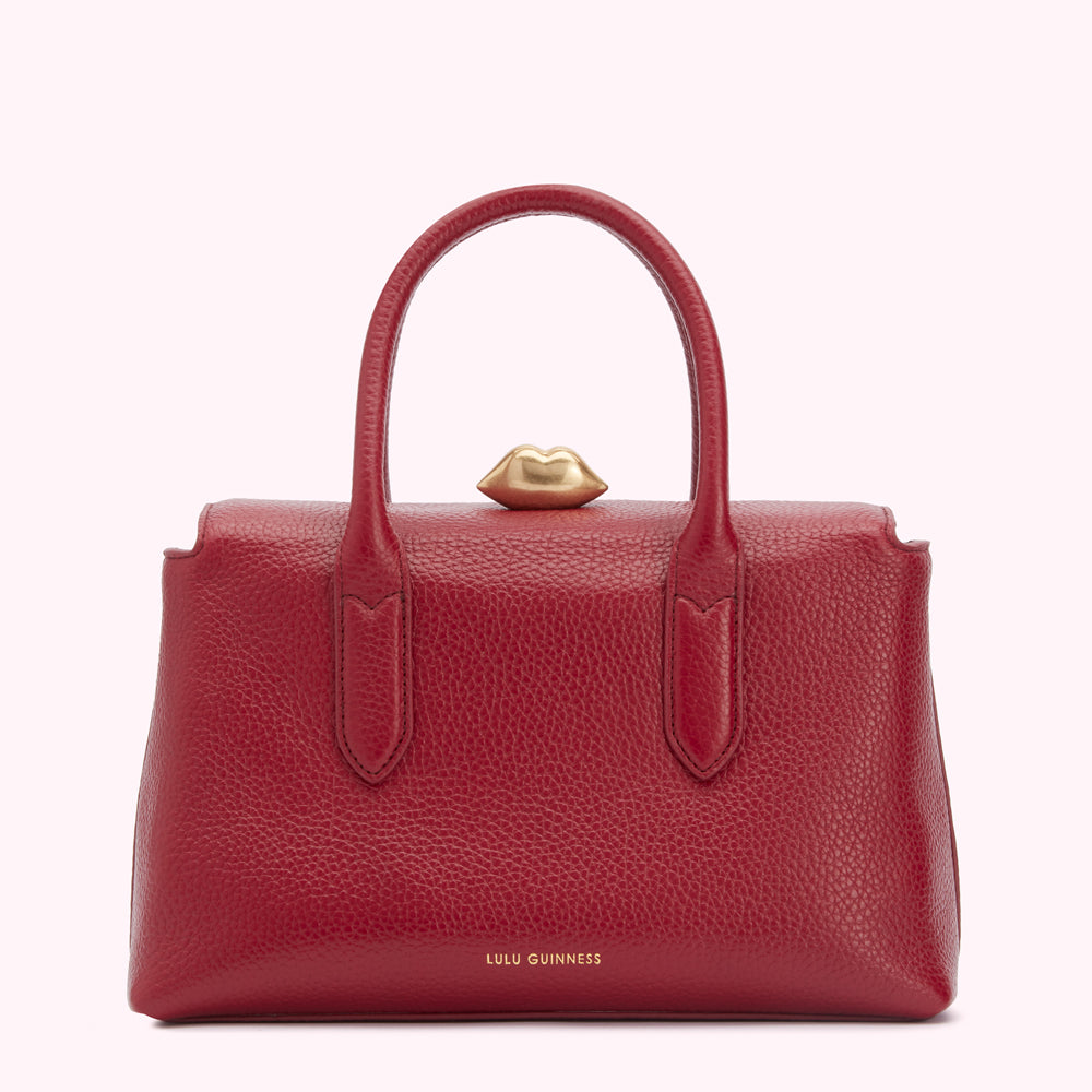 Red Lulu Guinness handbag with gold lip detail.
