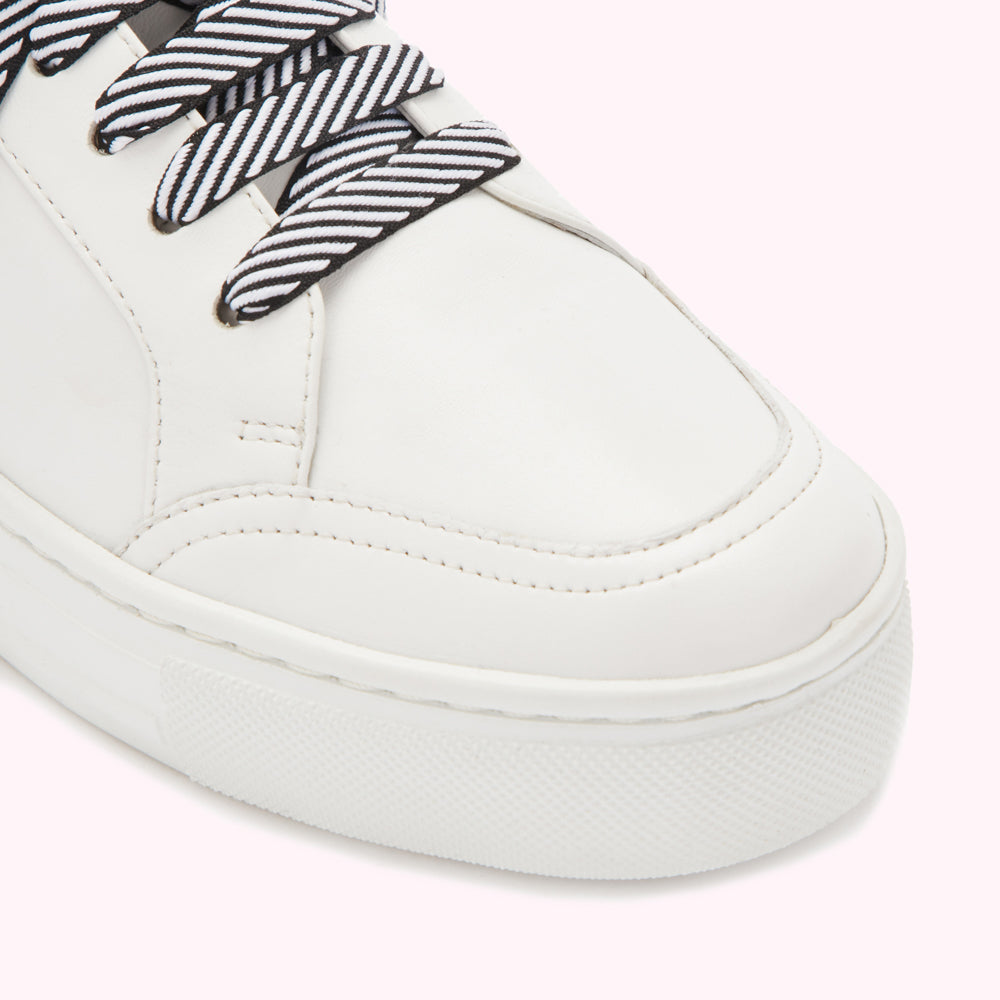 Close-up of a white leather sneaker with black and white striped laces.
