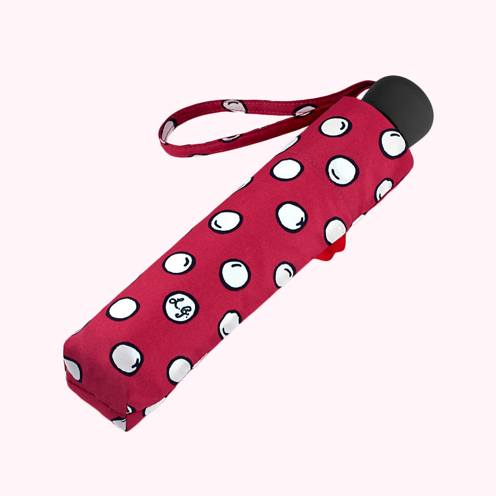 Red compact umbrella with white polka dots and a black handle.