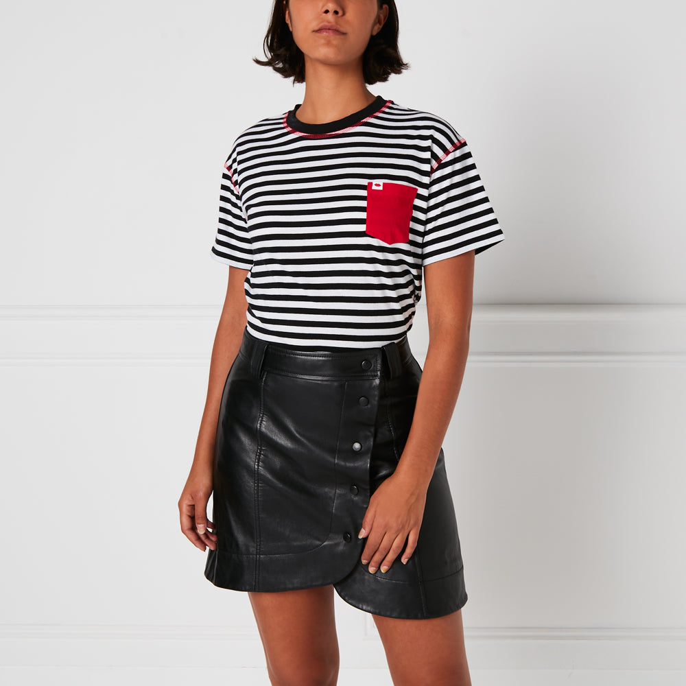 Woman wearing black and white striped shirt with red pocket and black leather mini skirt against white background.
