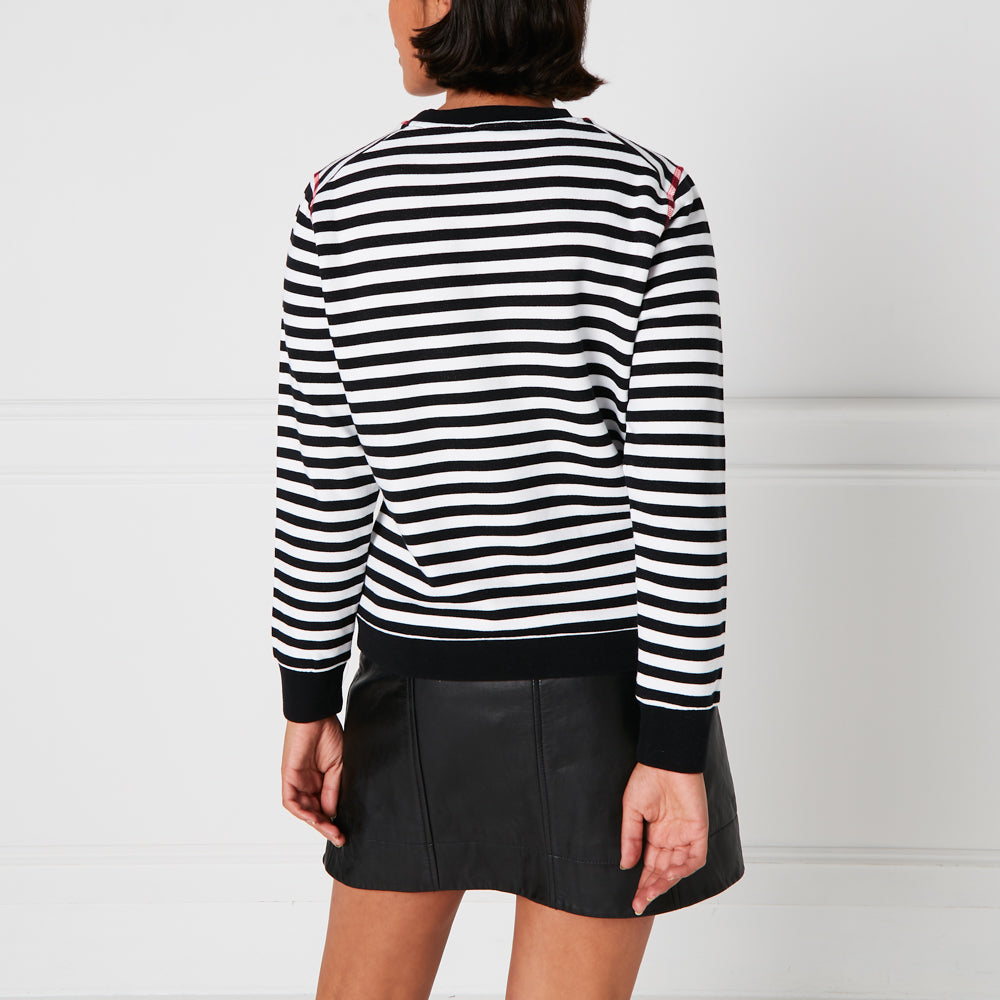 Woman wearing black and white striped sweater and black leather skirt, viewed from behind against a white background.
